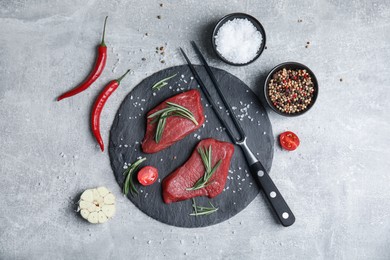 Fresh raw meat steaks and spices on light grey table, flat lay