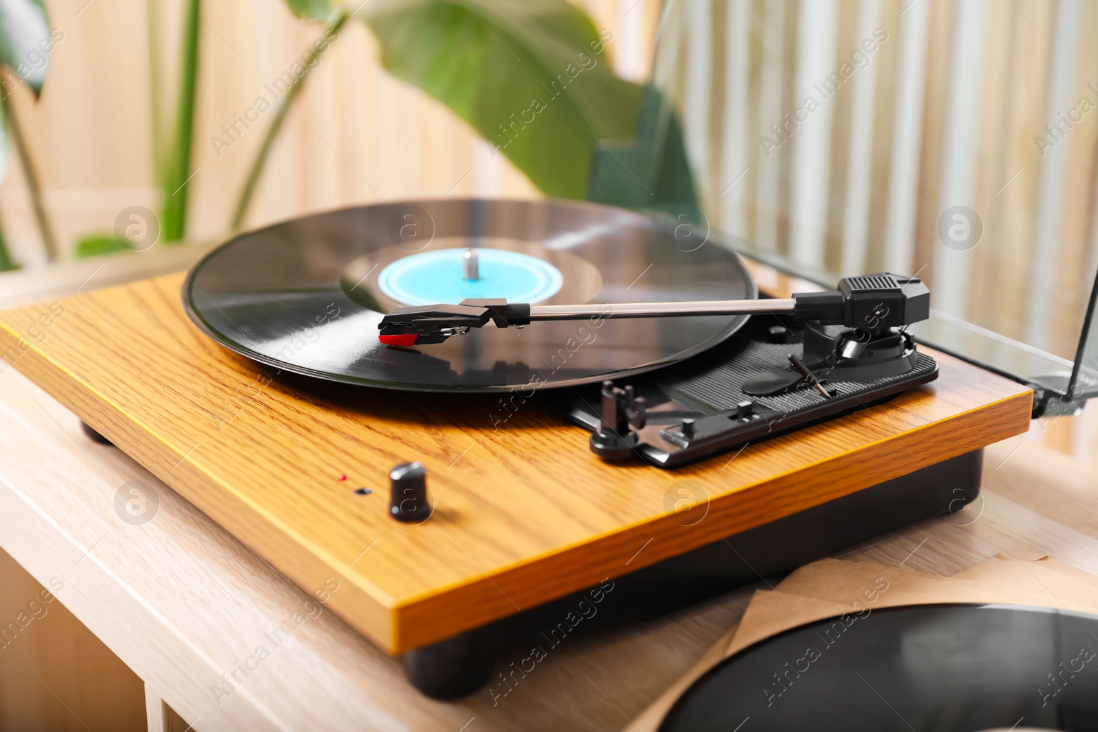 Photo of Stylish turntable with vinyl disc on light wooden table indoors