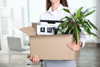 Young woman carrying box with stuff at office, closeup