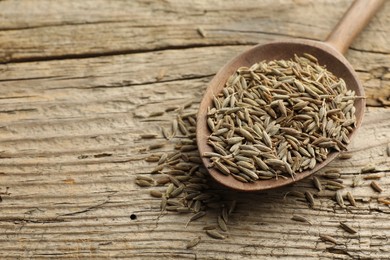 Photo of Spoon with caraway seeds on wooden table, closeup. Space for text