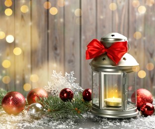 Image of Christmas lantern with burning candle and festive decor on wooden background