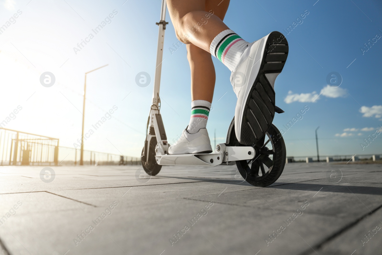 Photo of Woman riding kick scooter along city street, closeup