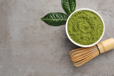 Photo of Green matcha powder, bamboo whisk and leaves on light grey table, flat lay. Space for text