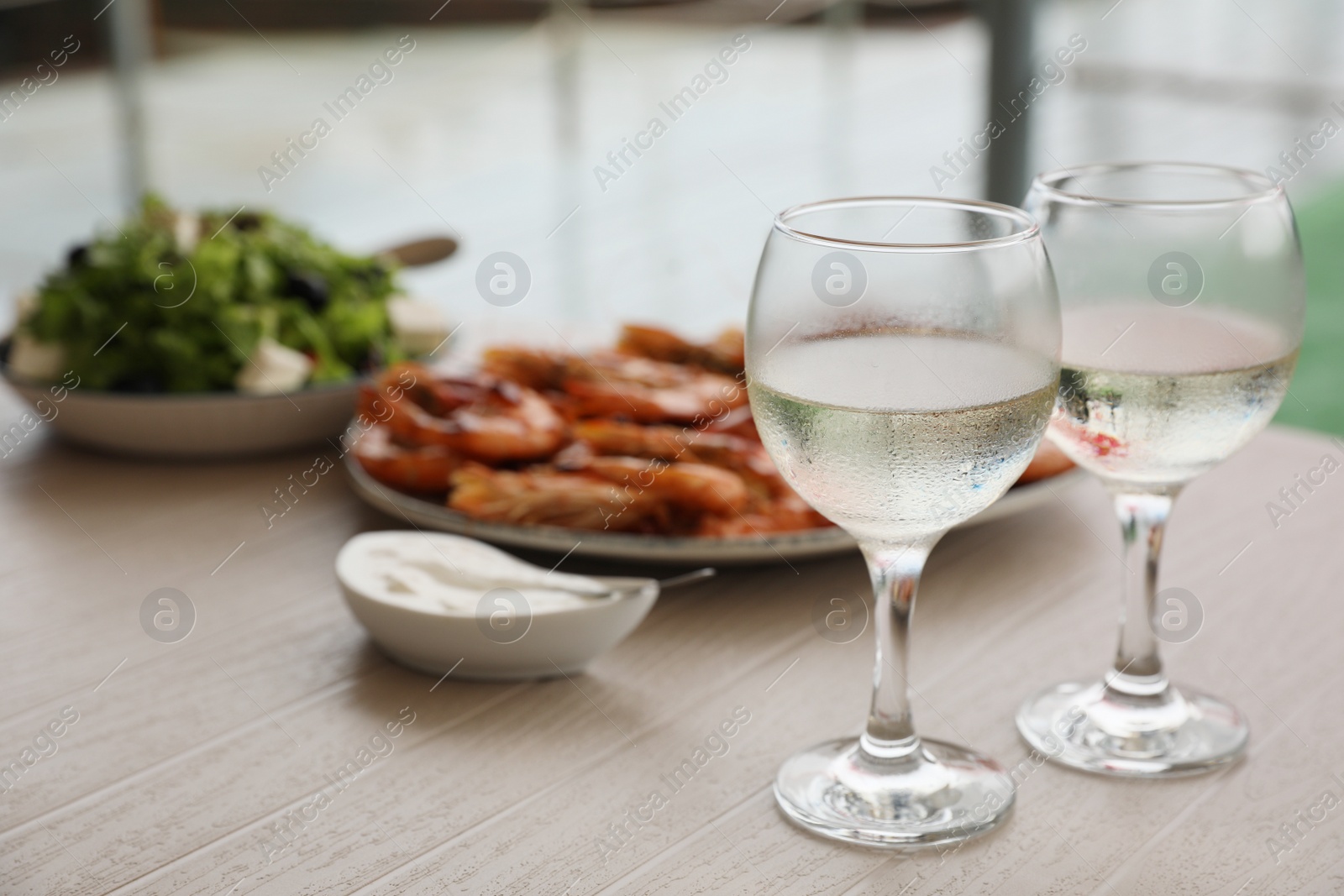 Photo of Glasses of white wine and delicious cooked shrimps served on wooden table