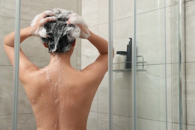 Photo of Woman washing hair in shower stall, back view