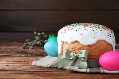 Photo of Easter cake and color eggs on wooden table, space for text