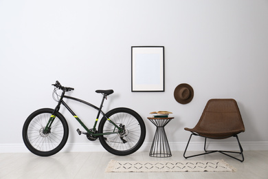 Photo of Modern bicycle and comfortable armchair in stylish living room interior