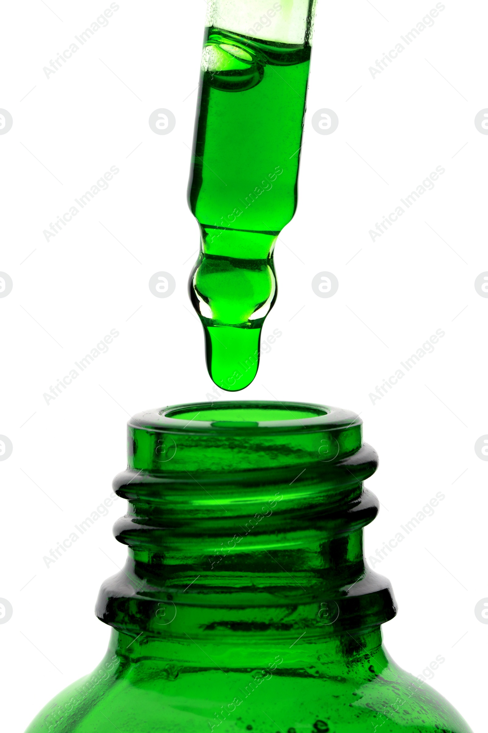 Photo of Dripping green facial serum from pipette into glass bottle on white background, closeup