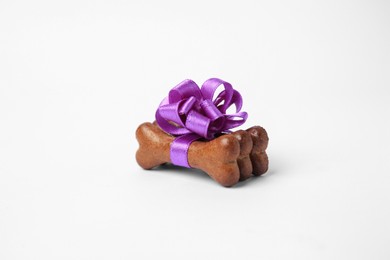 Photo of Bone shaped dog cookies with purple bow on white background