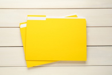 Yellow files with documents on white wooden table, top view
