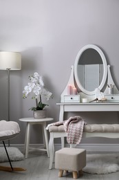 Wooden dressing table with decorative elements and makeup products in room. Interior design