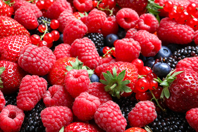 Photo of Mix of different ripe tasty berries as background, closeup view