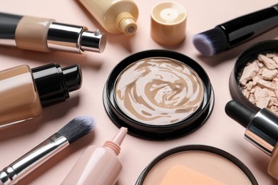 Photo of Different liquid foundations, beauty accessories and face powders on beige background, closeup