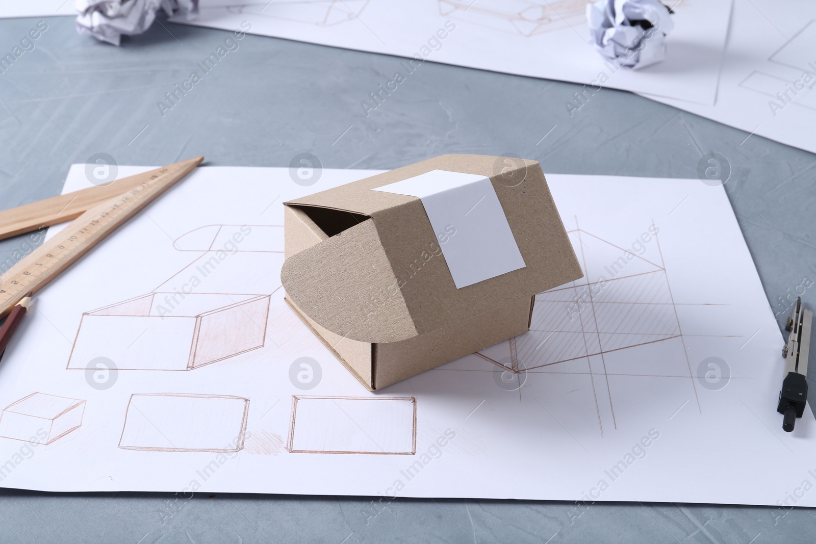 Photo of Creating packaging design. Drawing, box and stationery on blue textured table, closeup