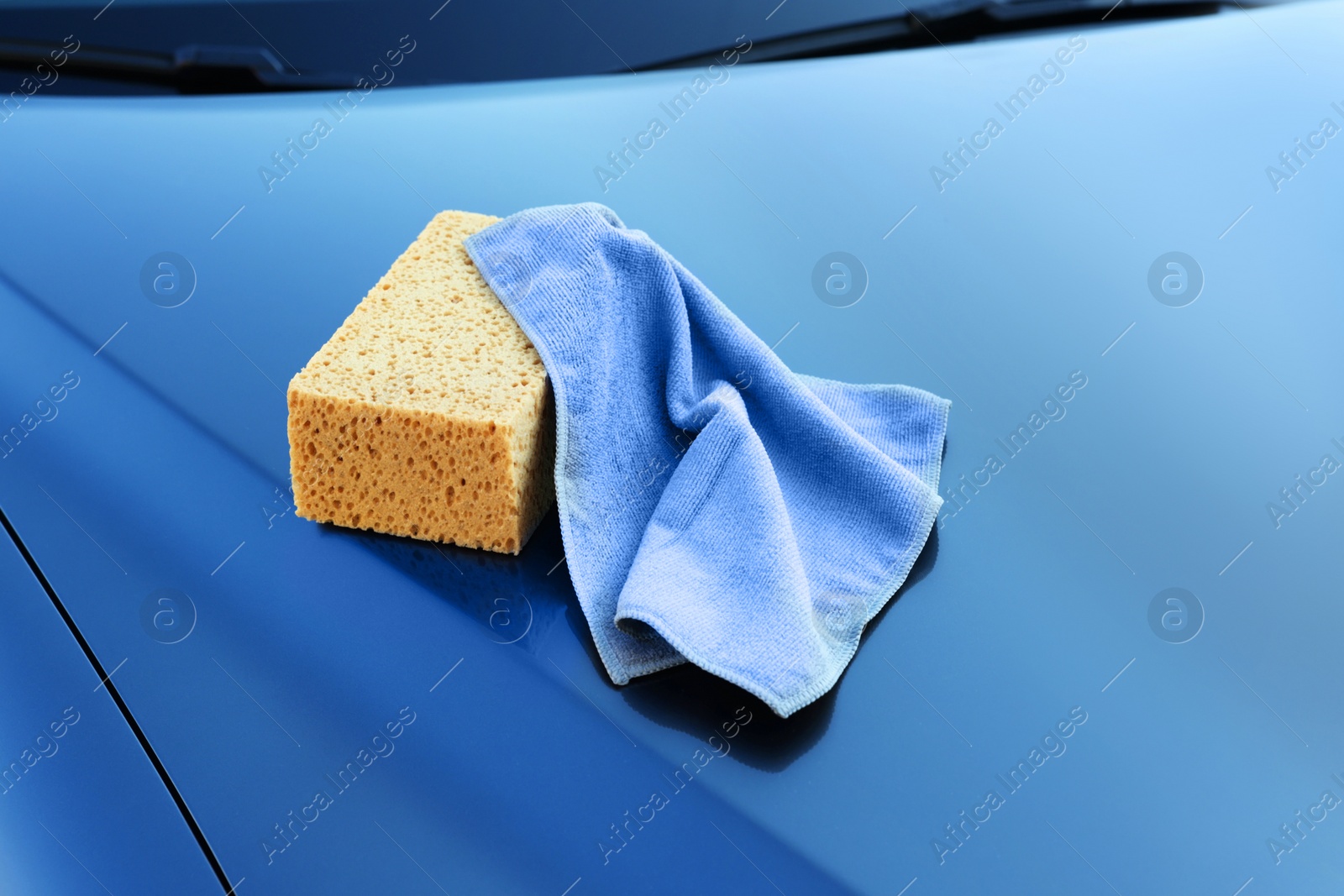 Photo of Sponge and rag on car hood. Cleaning products