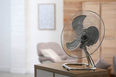 Photo of Modern electric fan on wooden table indoors. Space for text