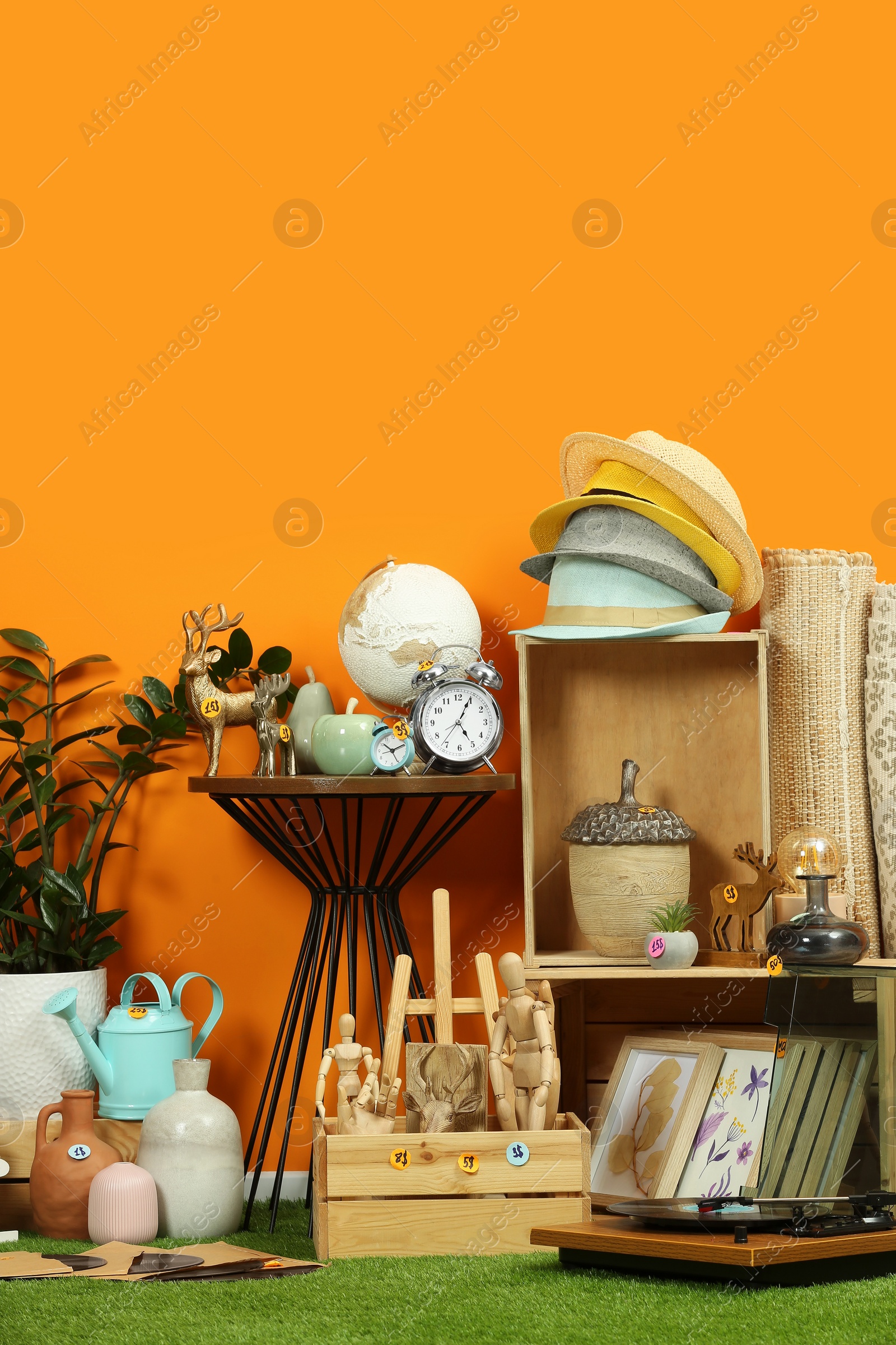 Photo of Many different items near orange wall in room. Garage sale