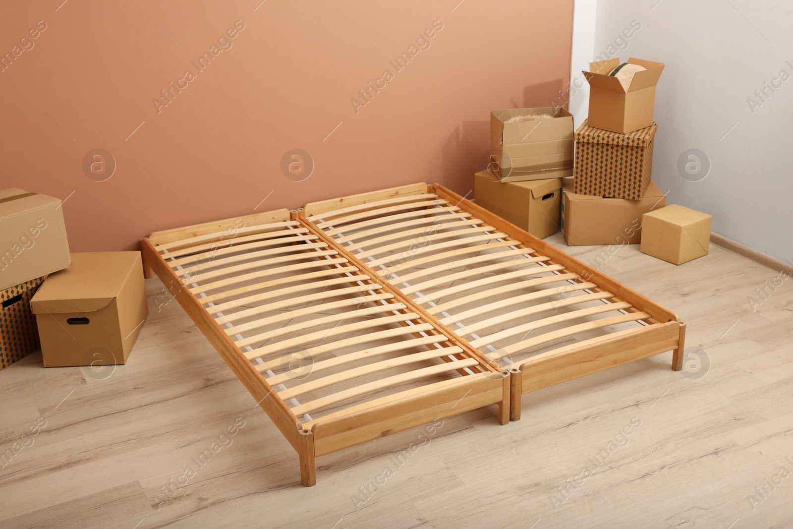 Photo of Wooden bed frame and cardboard boxes on floor in room