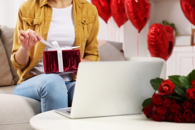 Photo of Valentine's day celebration in long distance relationship. Woman opening gift from her boyfriend at home, closeup