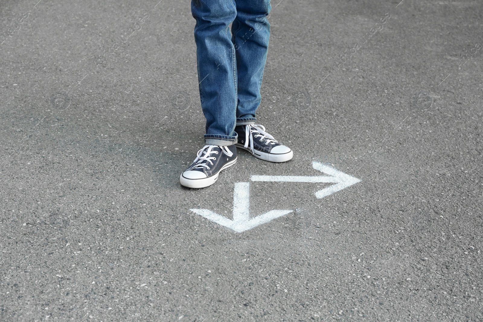 Photo of Woman standing near arrows on asphalt. Choice concept