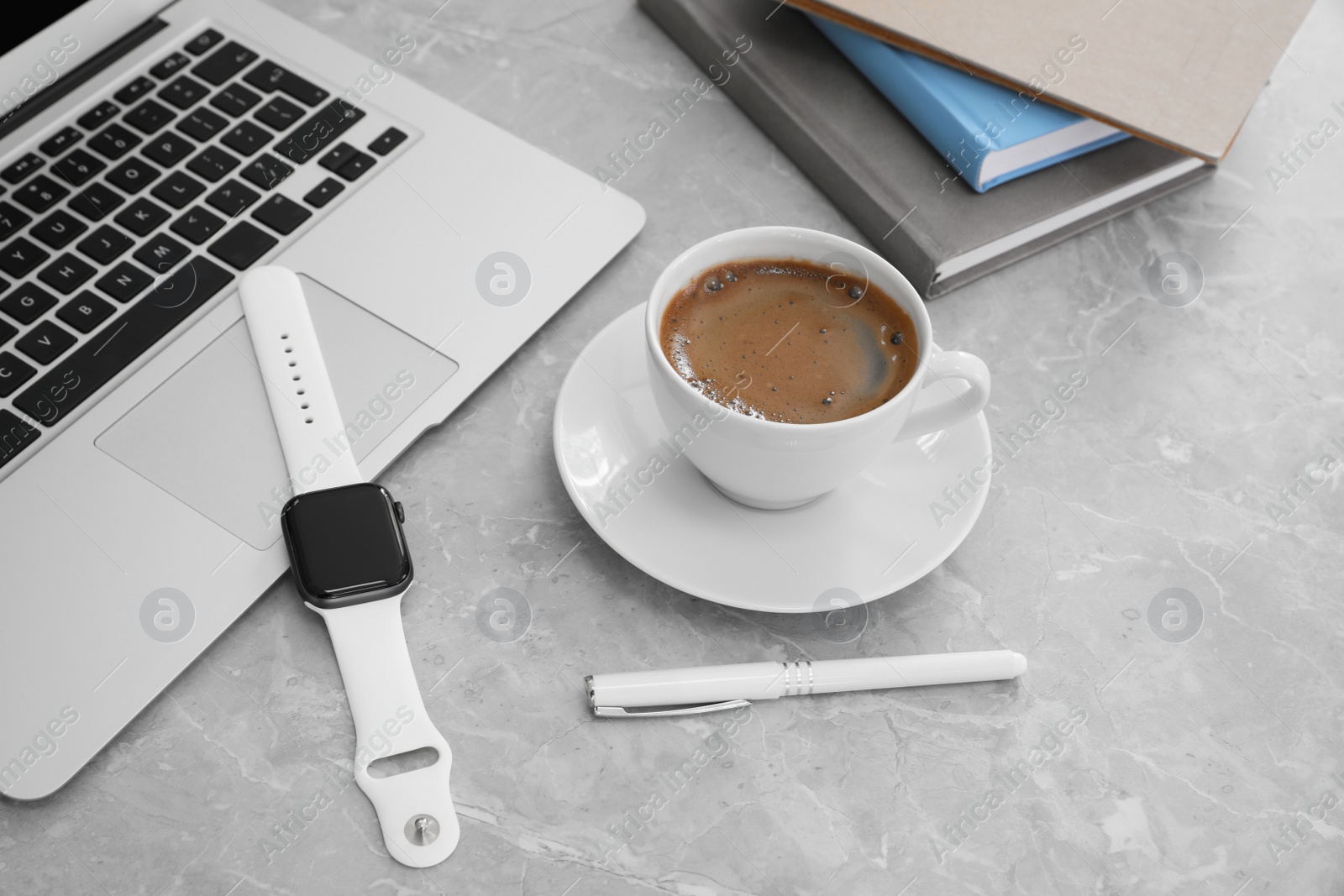 Image of Stylish smart watch, laptop and cup of coffee on grey marble table