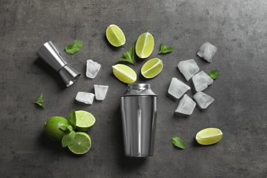 Photo of Flat lay composition with lime, mint and shaker on grey background. Refreshing beverage ingredients