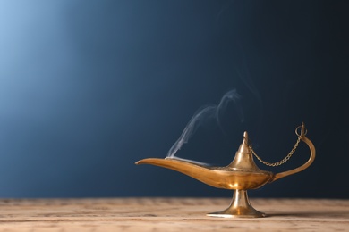 Aladdin lamp of wishes on wooden table against color background