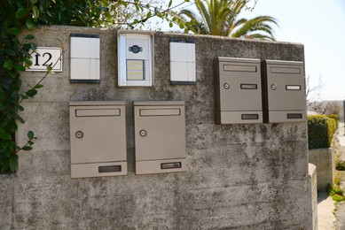 Mail boxes and intercoms on grey concrete wall outdoors