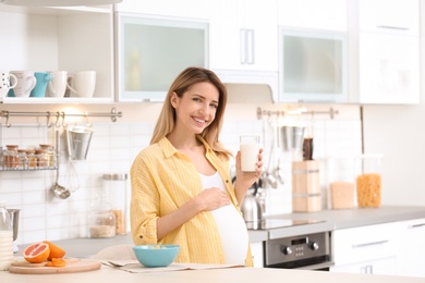Photo of Beautiful pregnant woman drinking milk in kitchen