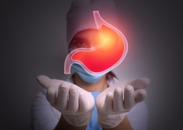 Image of Treatment of heartburn and other gastrointestinal diseases. Doctor holding stomach illustration on dark background,