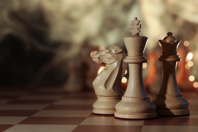 Wooden king, queen and knight on chessboard, selective focus. Space for text