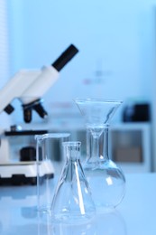 Photo of Laboratory analysis. Different glassware and microscope on white table indoors