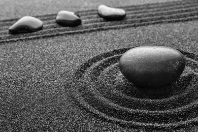 Photo of Black sand with stones and beautiful pattern. Zen concept