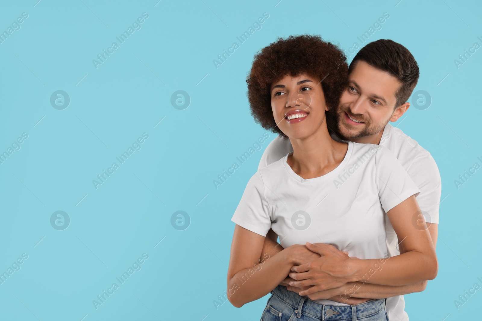 Photo of International dating. Happy couple hugging on light blue background, space for text