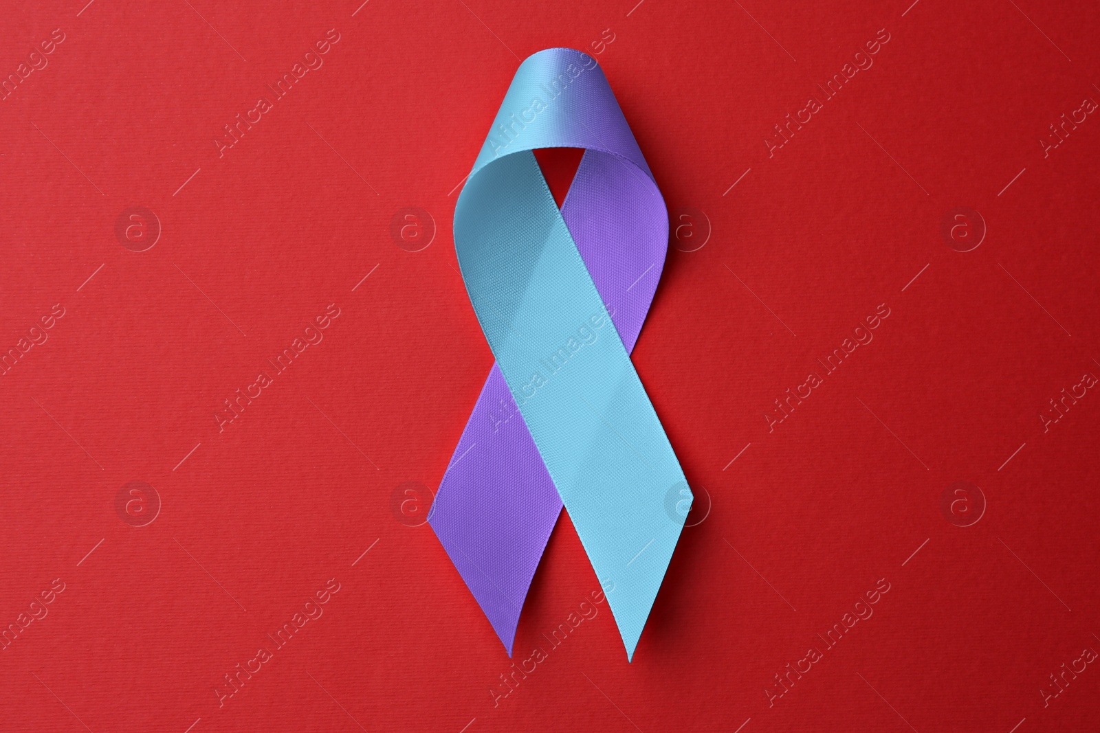 Image of World Arthritis Day. Blue and purple awareness ribbon on red background, top view