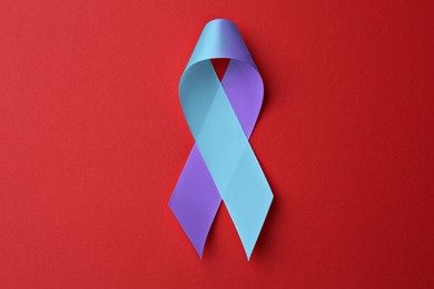 World Arthritis Day. Blue and purple awareness ribbon on red background, top view