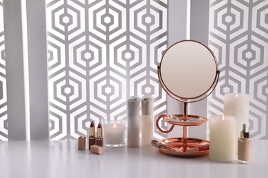 Small round mirror, cosmetic products and accessories on white table indoors