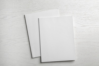 Brochures with blank cover on wooden background, top view. Mock up for design