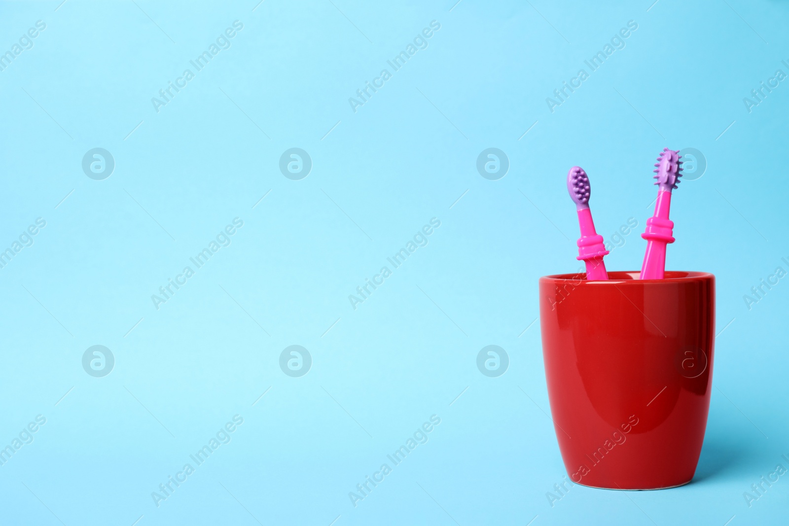 Photo of Baby toothbrushes in holder and space for text on color background