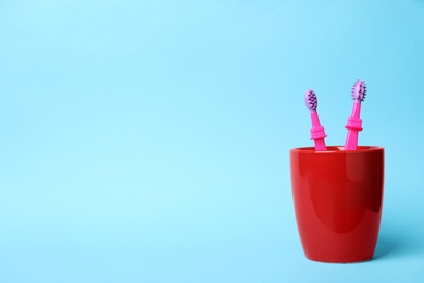 Baby toothbrushes in holder and space for text on color background