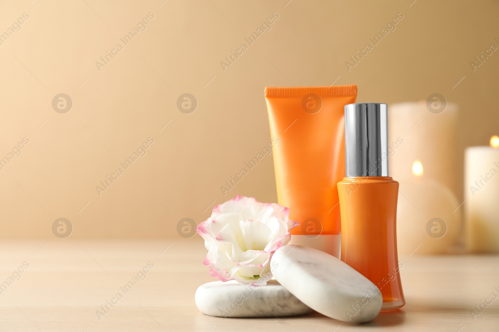 Photo of Cosmetic products, flower and spa stones on wooden table. Space for text