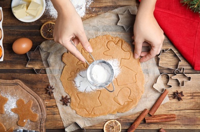 Woman making Christmas cookies at wooden table, top view