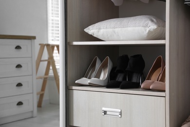 Photo of Wardrobe closet with different stylish shoes and home stuff in room