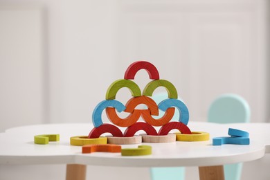 Photo of Colorful wooden pieces of playing set on white table indoors. Educational toy for motor skills development