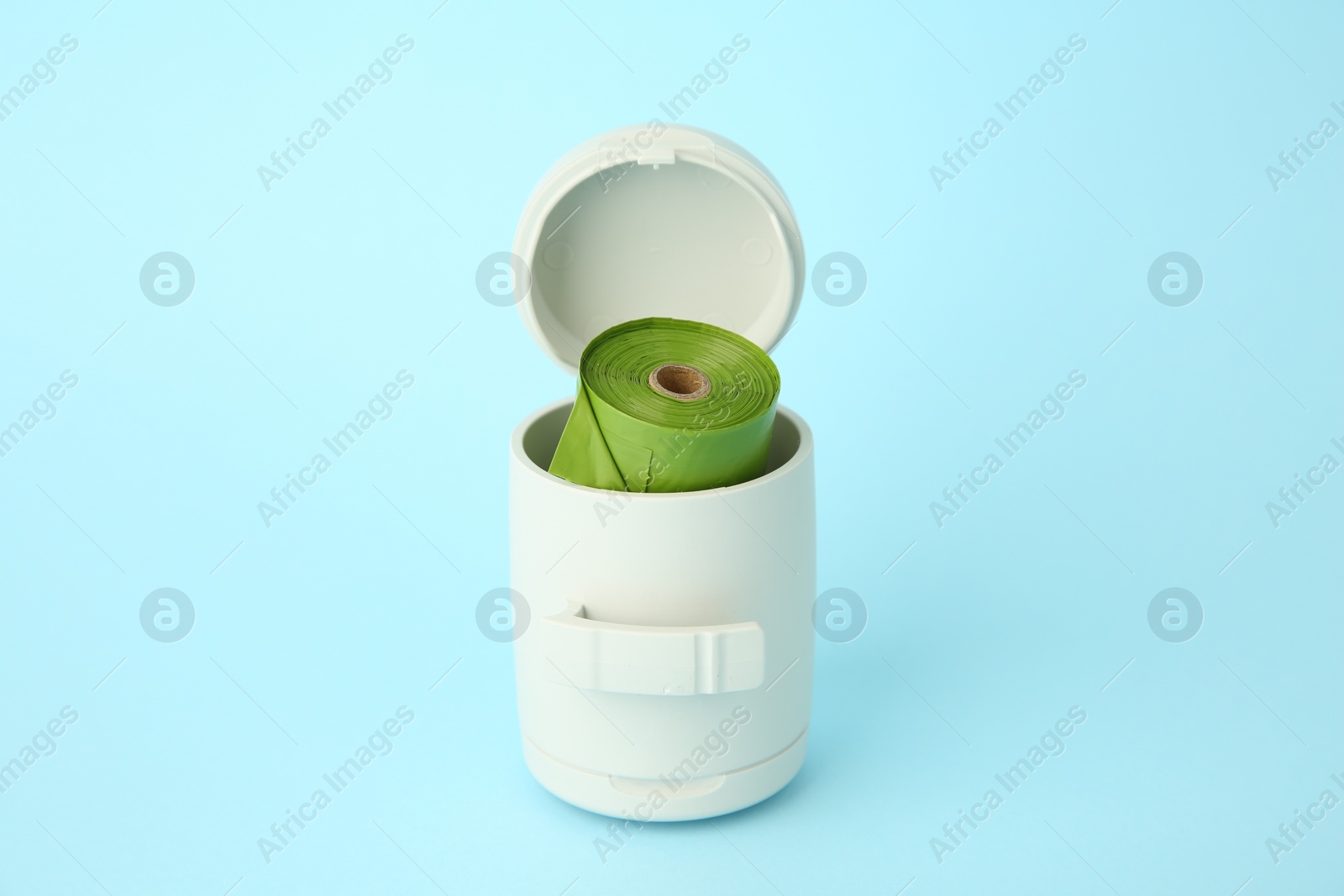 Photo of Dispenser with dog waste bags on light blue background