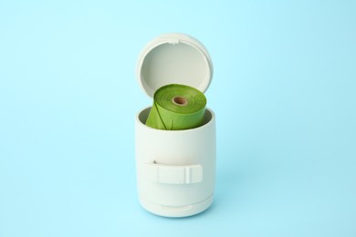 Dispenser with dog waste bags on light blue background