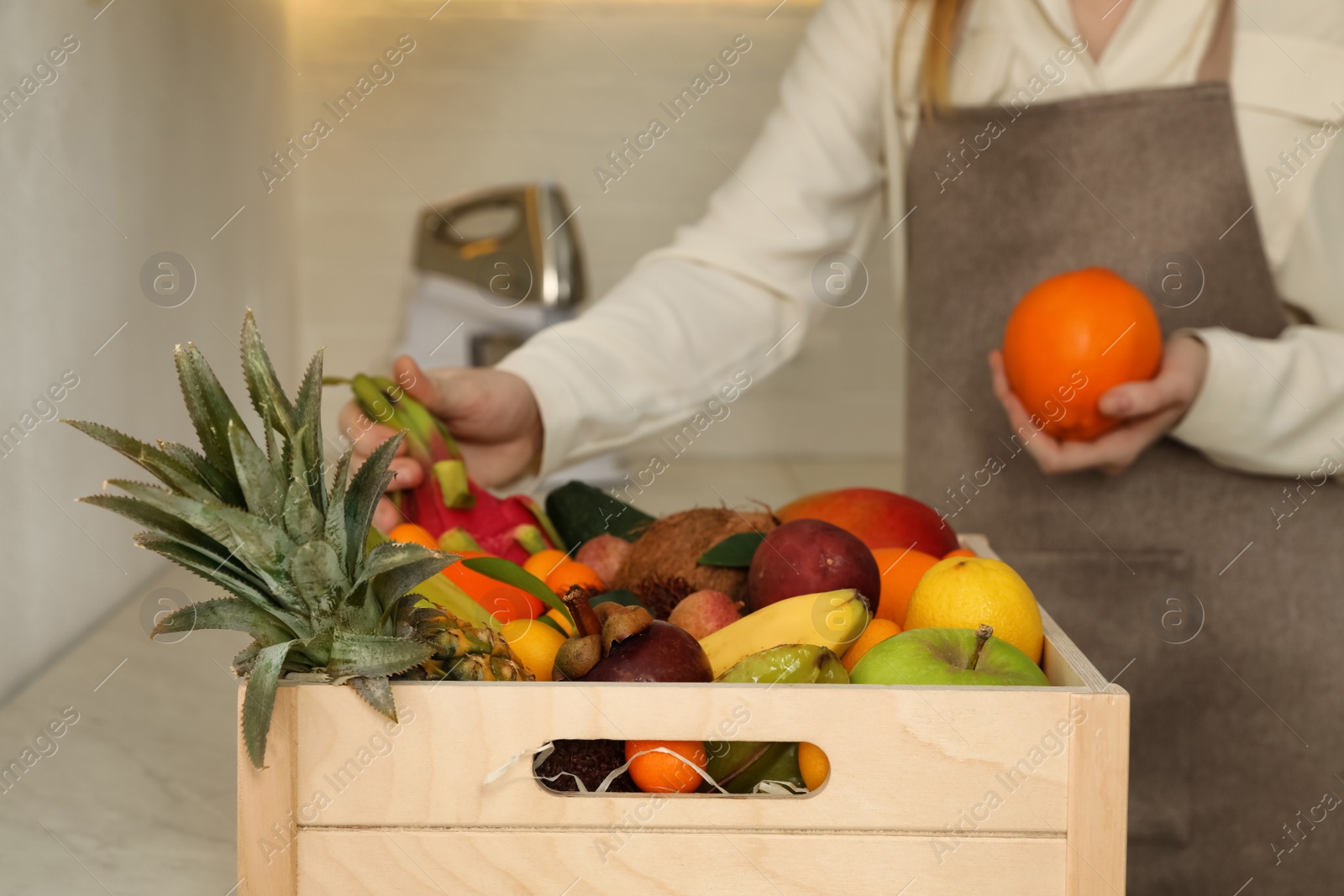 Photo of Woman with assortment of exotic fruits at table in kitchen, closeup