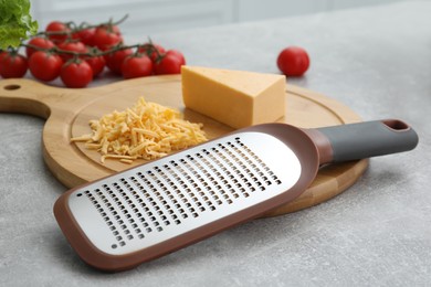 Photo of Wooden board with grater and cheese on grey table