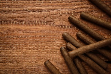 Photo of Many cigars on wooden table, flat lay. Space for text