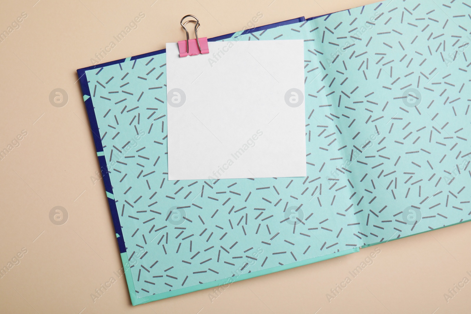 Photo of Notebook and note with paper clip on beige background, top view